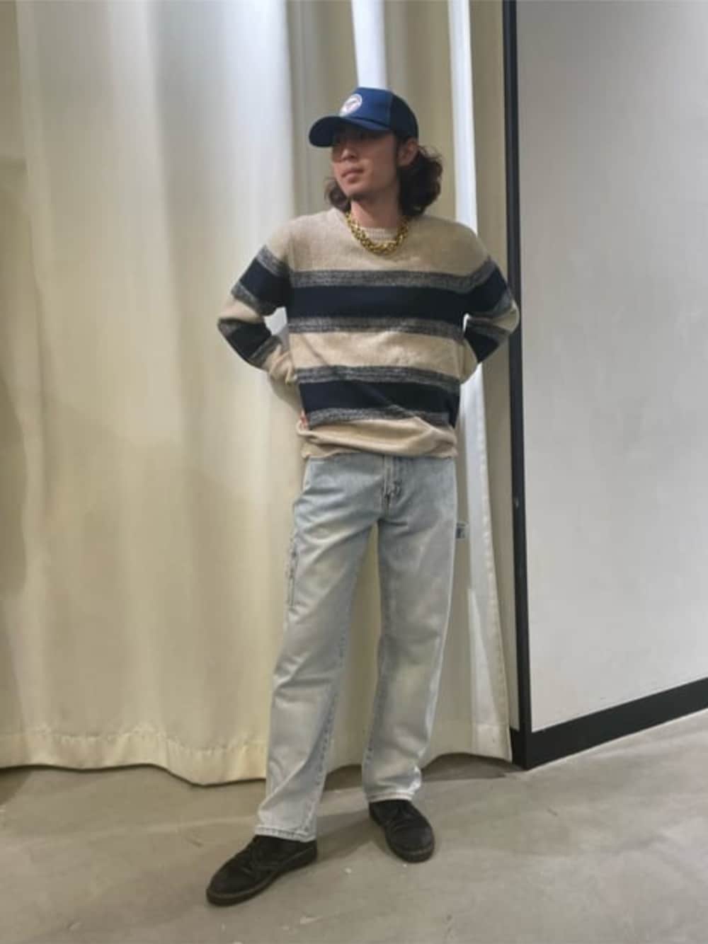 ブルー系のデニムパンツ、ベージュ系のニット/セーター、ゴールド系のネックレスを着用したメンズの秋コーディネートの1枚目の写真