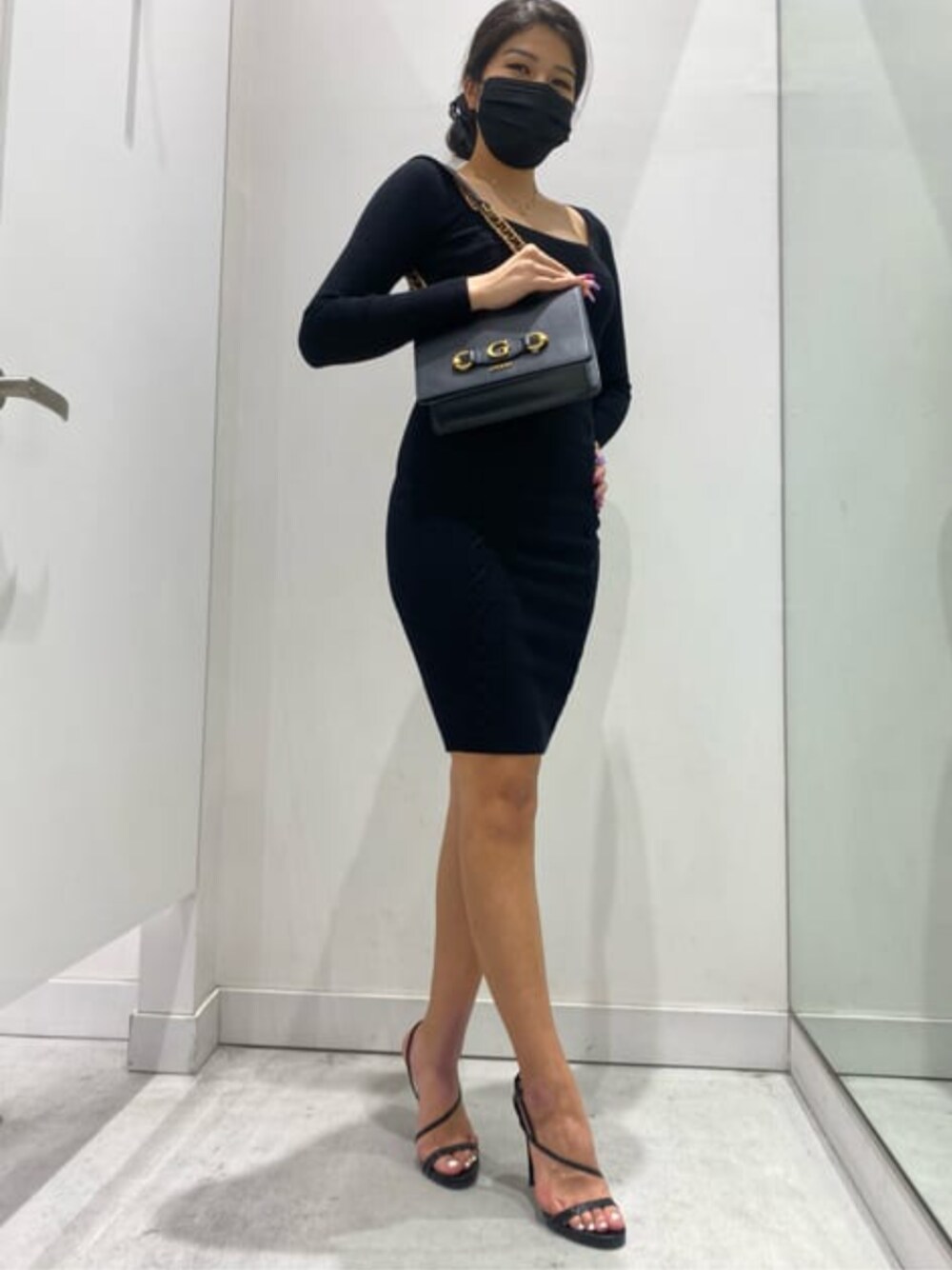 ブラック系のショルダーバッグ、ブラック系のワンピース、ゴールド系のネックレスを着用したレディースの秋コーディネートの1枚目の写真