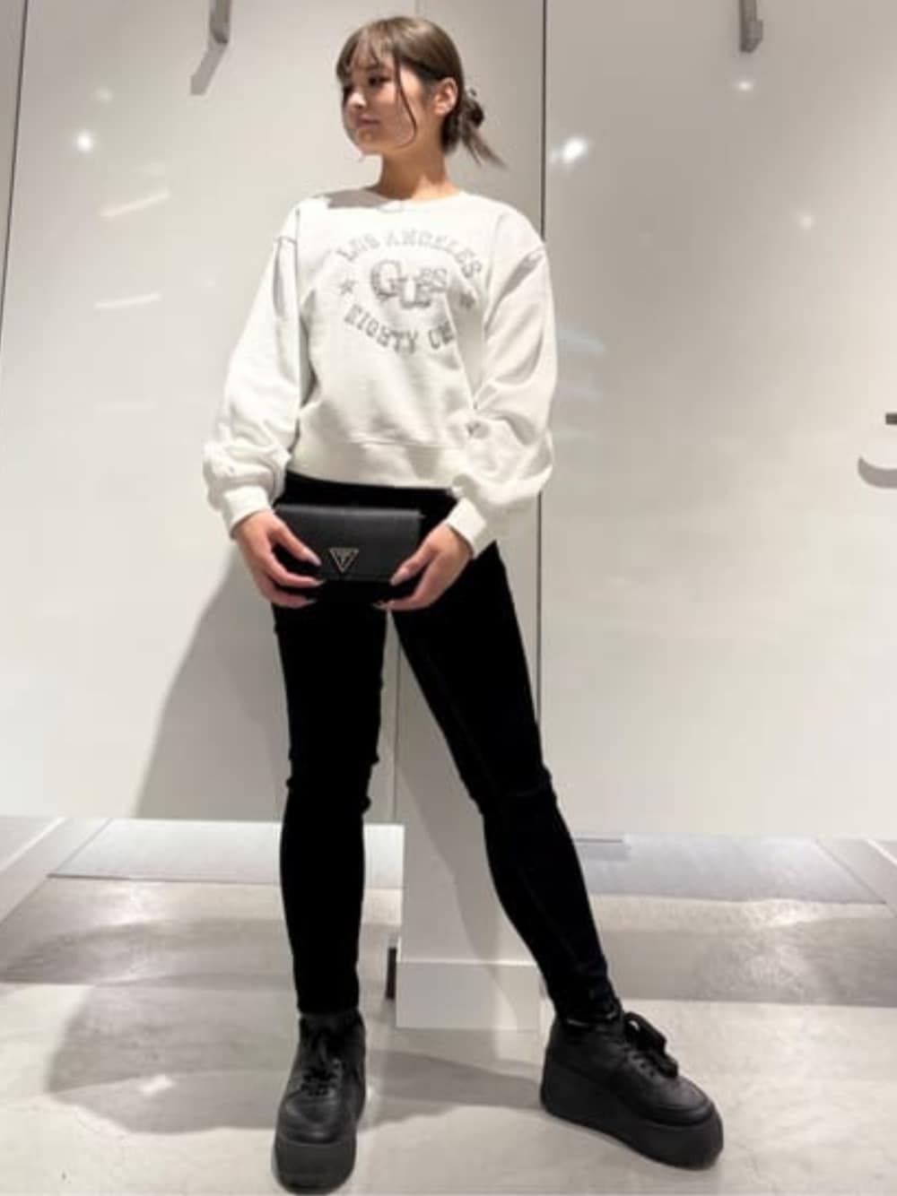 ブラック系のショルダーバッグ、ブルー系のデニムパンツ、ホワイト系のスウェットを着用したレディースの冬コーディネートの1枚目の写真