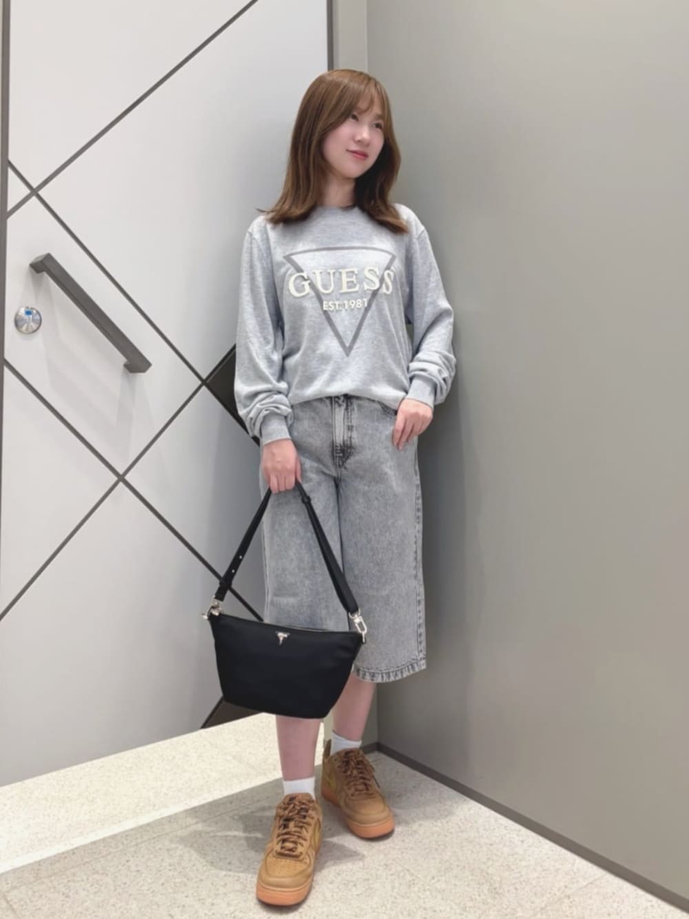 ブラック系のハンドバッグ、グレー系のデニムパンツ、グレー系のニット/セーターを着用したレディースの夏コーディネートの1枚目の写真