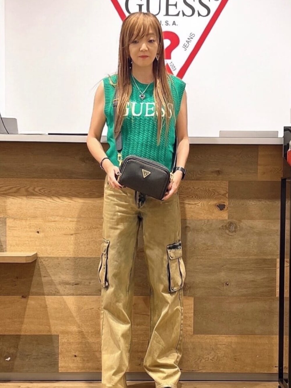 イエロー系のカーゴパンツ、グリーン系のタンクトップ、ブラック系のショルダーバッグを着用したレディースの夏コーディネートの1枚目の写真