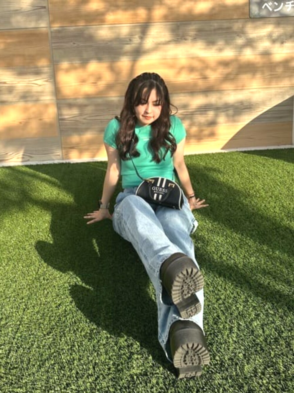 ブルー系のデニムパンツ、ブラック系のハンドバッグ、グリーン系のTシャツ/カットソーを着用したレディースの春コーディネートの1枚目の写真