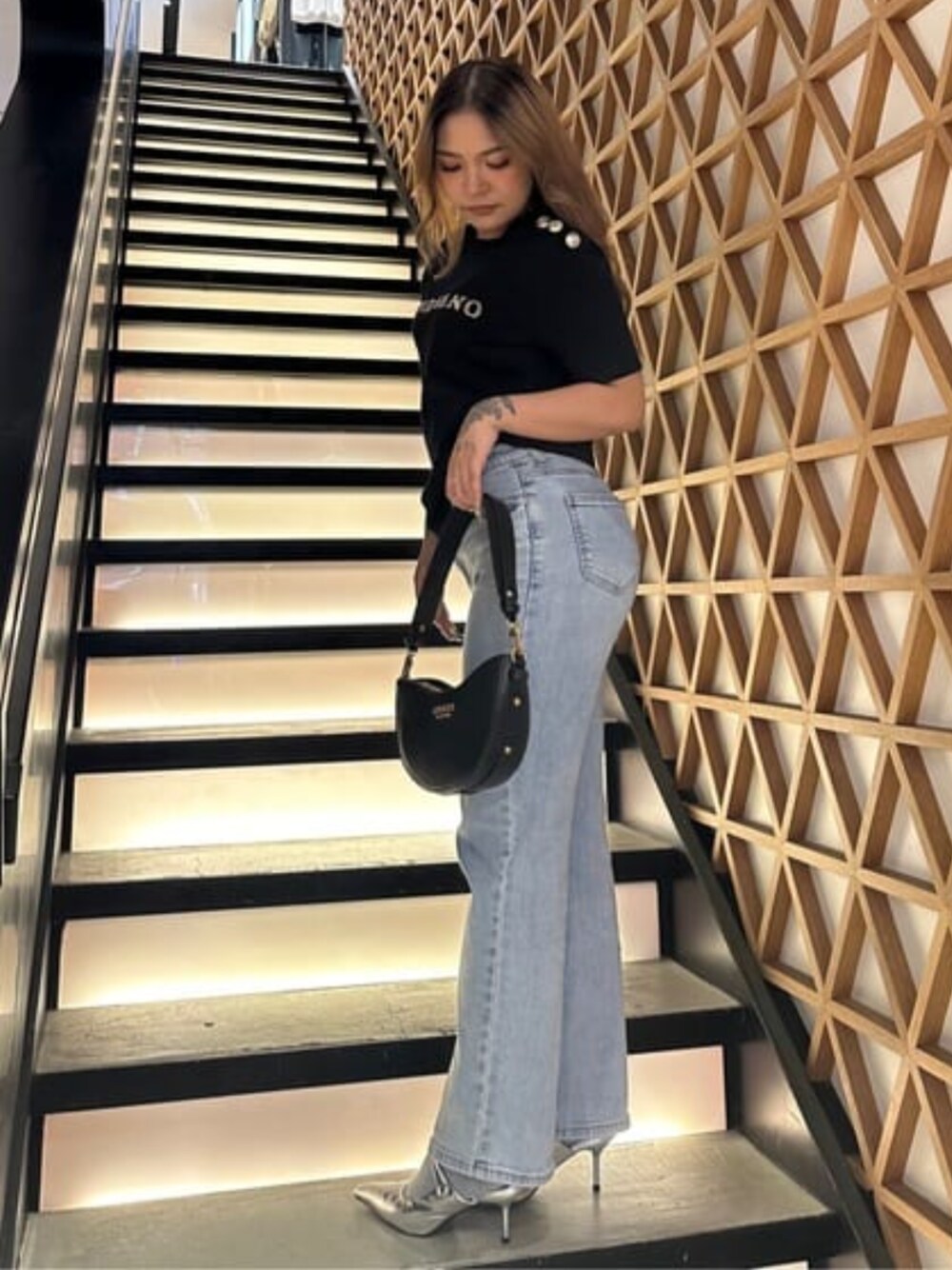 ブルー系のデニムパンツ、ブラック系のショルダーバッグを着用したレディースの春コーディネートの1枚目の写真