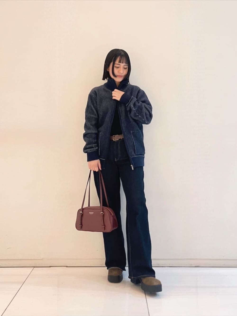 ブラック系のニット/セーター、レッド系のショルダーバッグ、ブルー系のブルゾンを着用したレディースの冬コーディネートの1枚目の写真