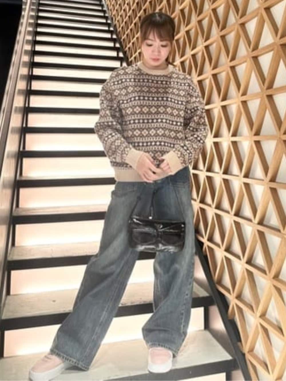 ブルー系のデニムパンツ、ブラウン系のニット/セーター、ブラック系のショルダーバッグを着用したレディースの春コーディネートの1枚目の写真