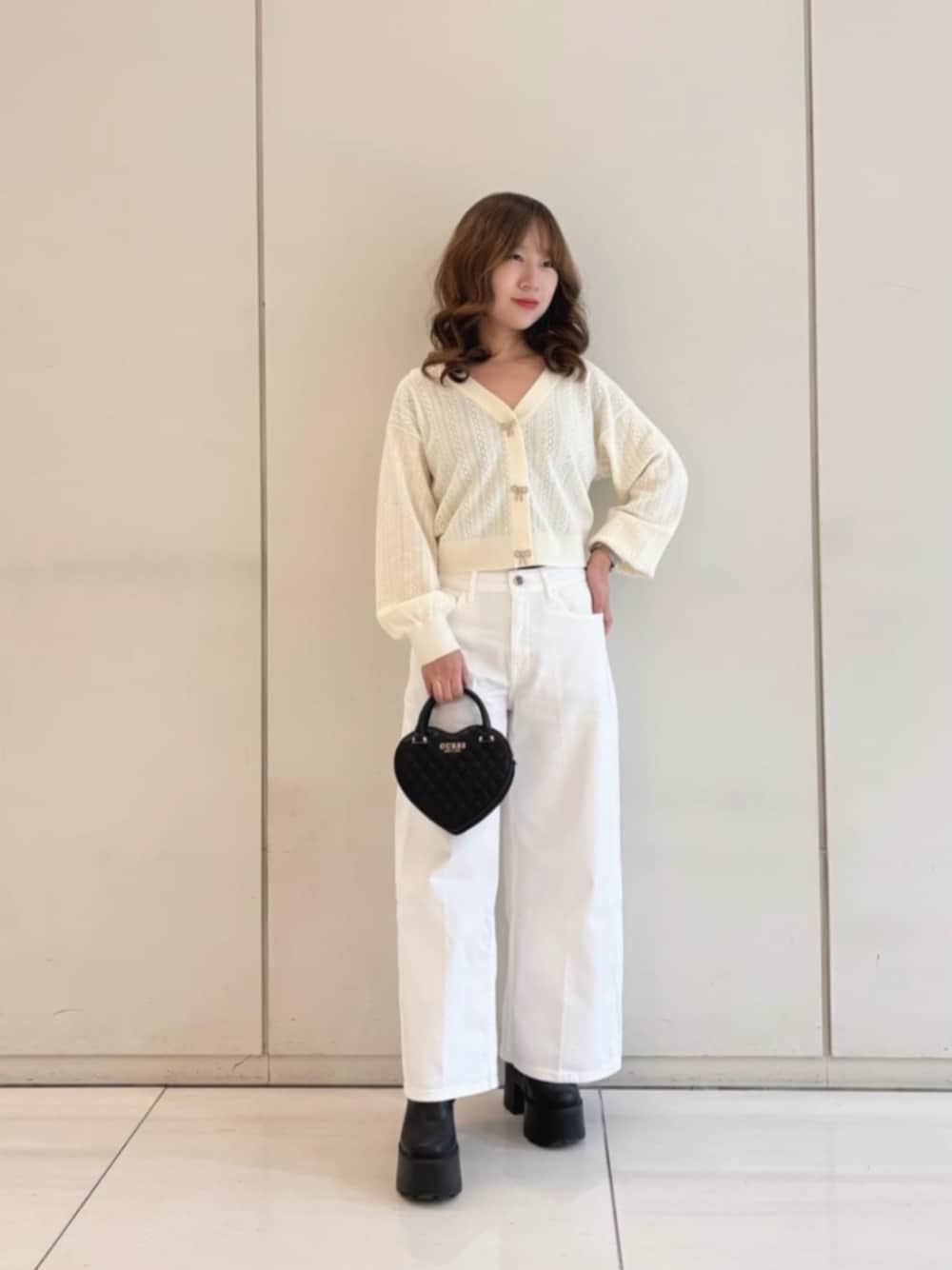 ホワイト系のデニムパンツ、ブラック系のショルダーバッグ、ベージュ系のカーディガン/ボレロを着用したレディースの冬コーディネートの1枚目の写真