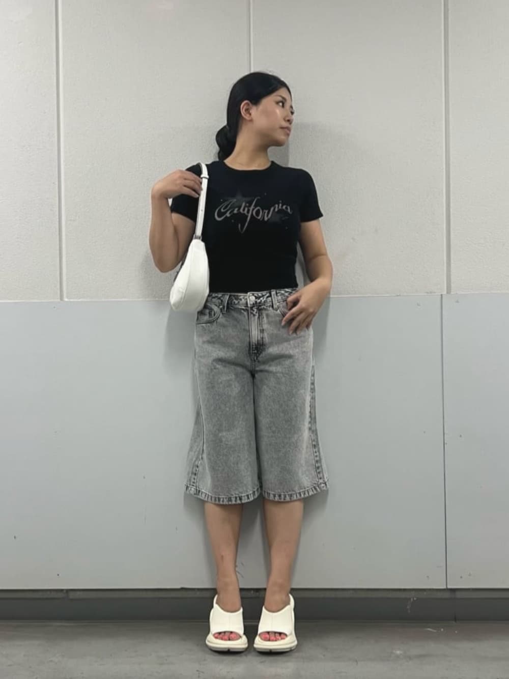 グレー系のデニムパンツ、ブラック系のTシャツ/カットソー、ホワイト系のハンドバッグを着用したレディースの夏コーディネートの1枚目の写真