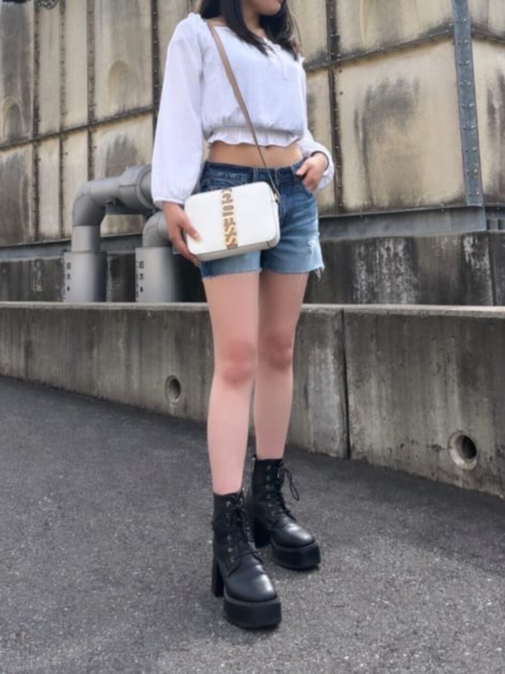 ホワイト系のショルダーバッグ、ブルー系のデニムパンツを着用したレディースの夏コーディネートの1枚目の写真
