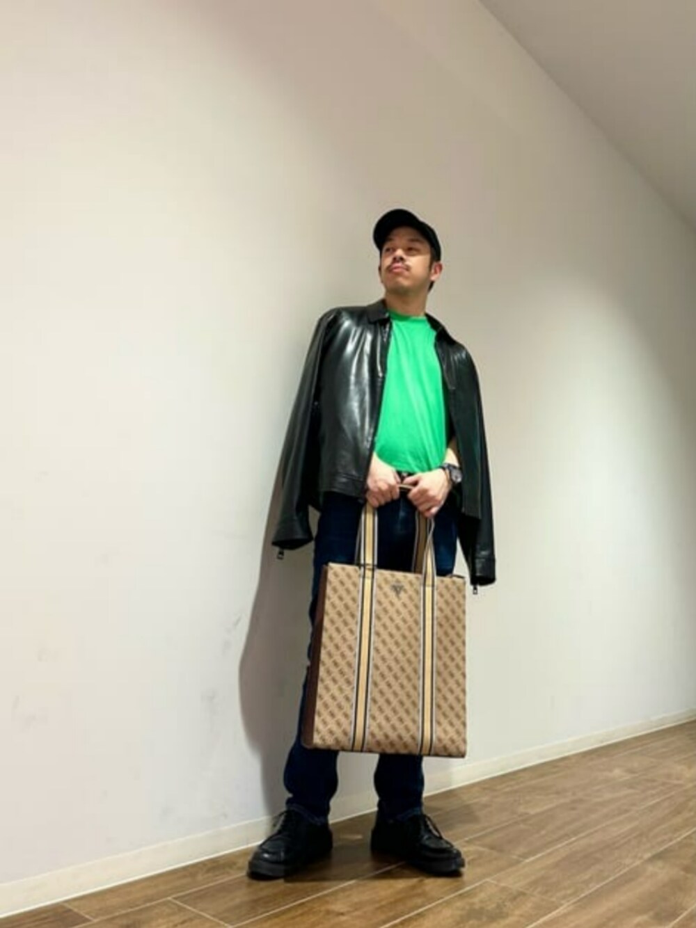 ブルー系のデニムパンツ、ブラック系のブルゾン、ベージュ系のトートバッグを着用したメンズの秋コーディネートの1枚目の写真