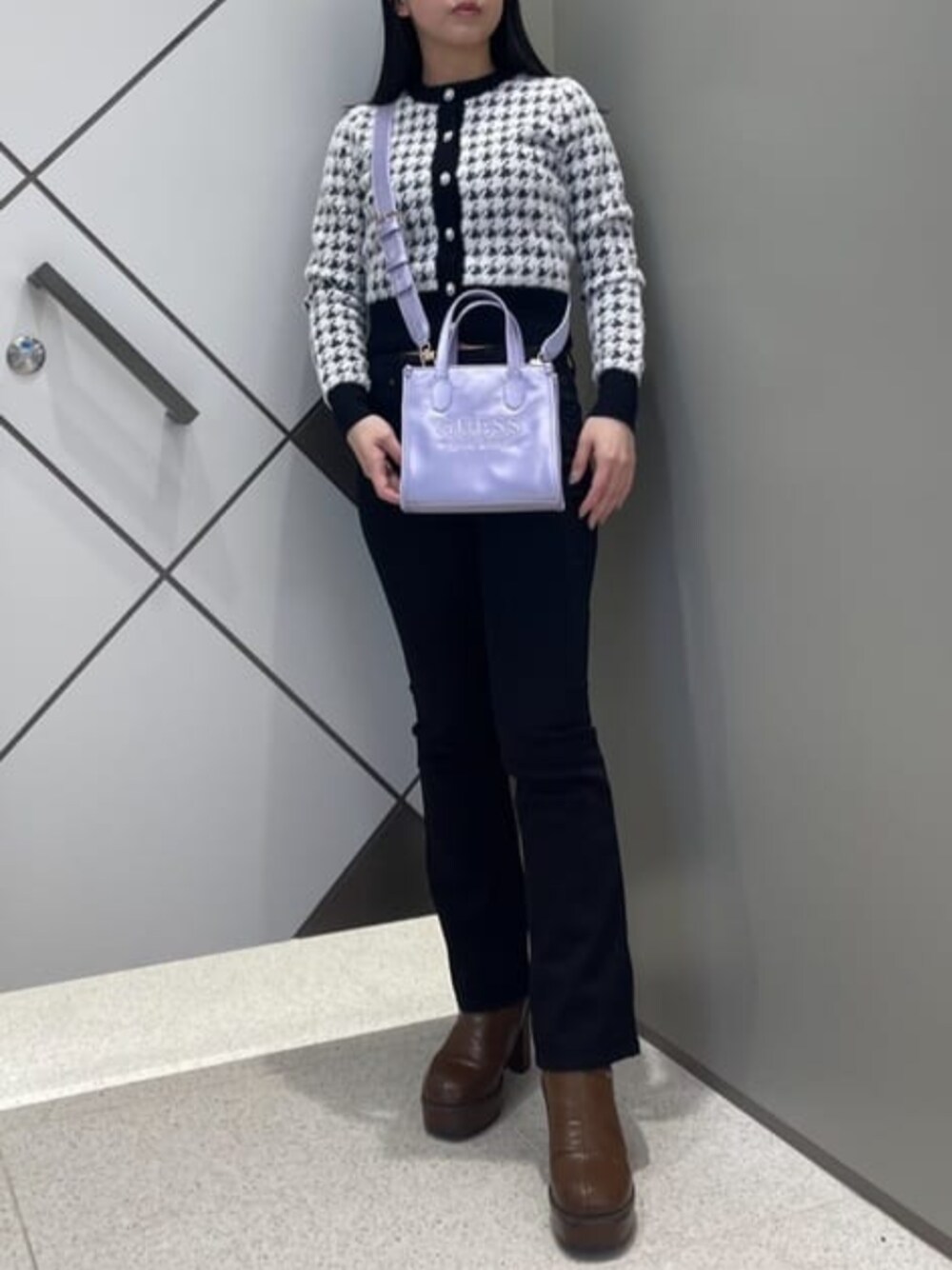 ブラック系のデニムパンツ、ブラック系のカーディガン/ボレロ、パープル系のショルダーバッグを着用したレディースの春コーディネートの1枚目の写真