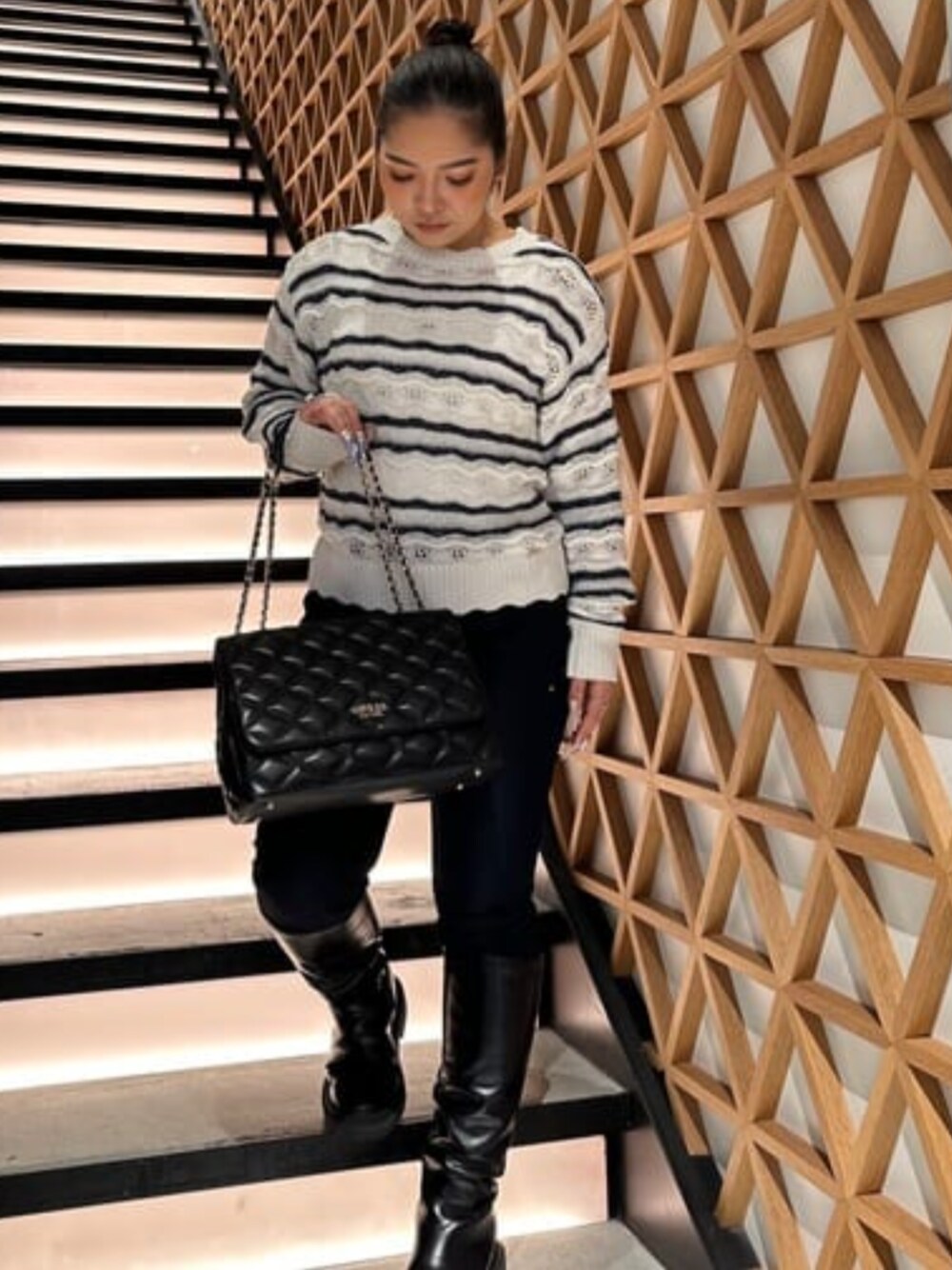 ホワイト系のニット/セーター、ブルー系のデニムパンツ、ブラック系のショルダーバッグを着用したレディースの春コーディネートの1枚目の写真