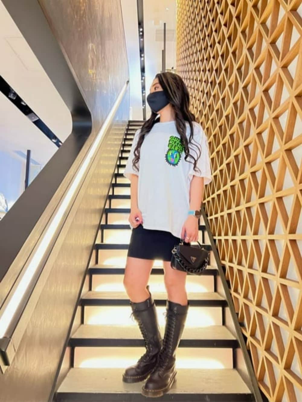 ブラック系のハンドバッグ、ブラック系のワンピース、ホワイト系のTシャツ/カットソーを着用したレディースの夏コーディネートの1枚目の写真