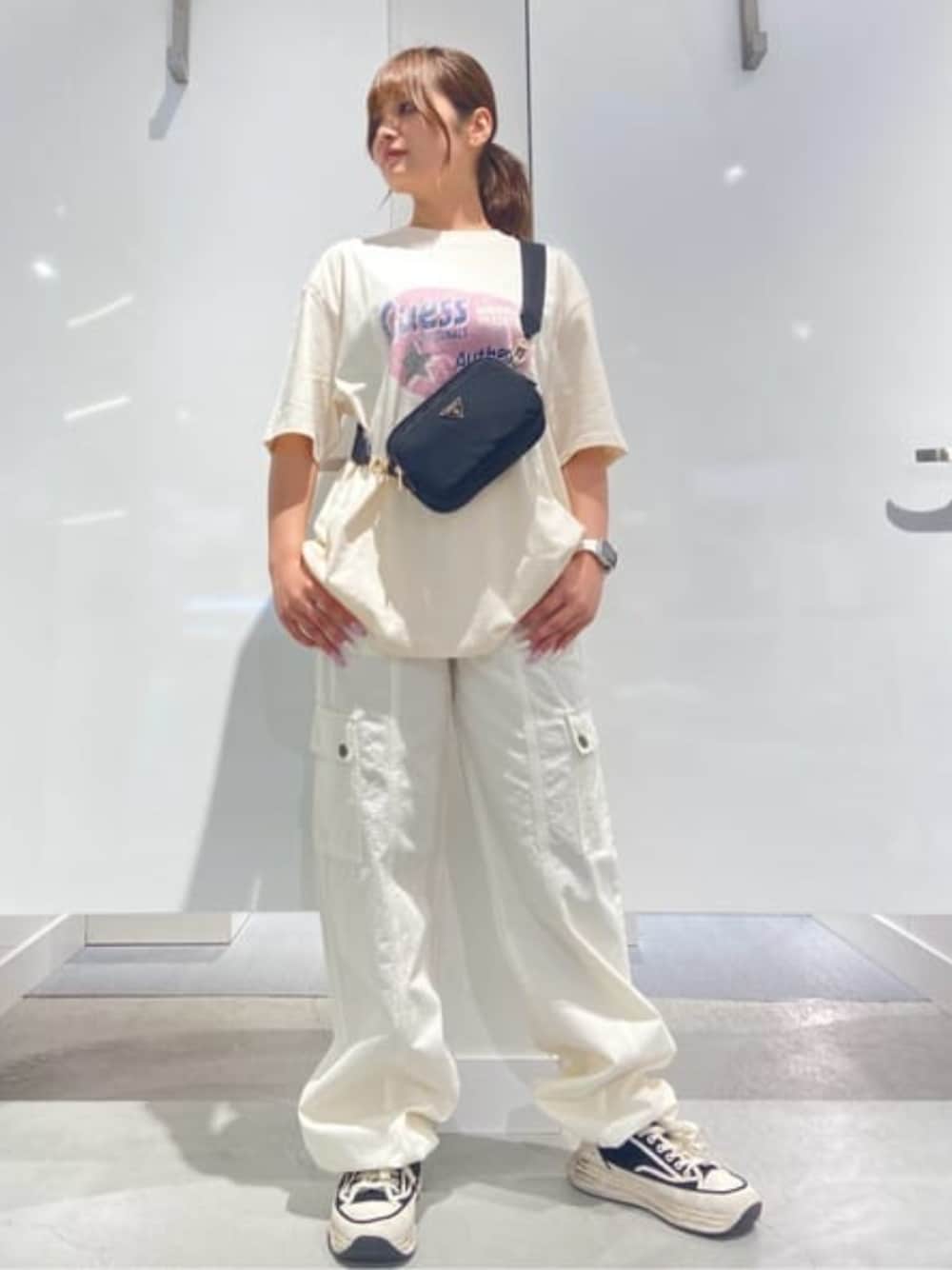 ブラック系のショルダーバッグ、ホワイト系のTシャツ/カットソー、ホワイト系のカーゴパンツを着用したレディースの秋コーディネートの1枚目の写真