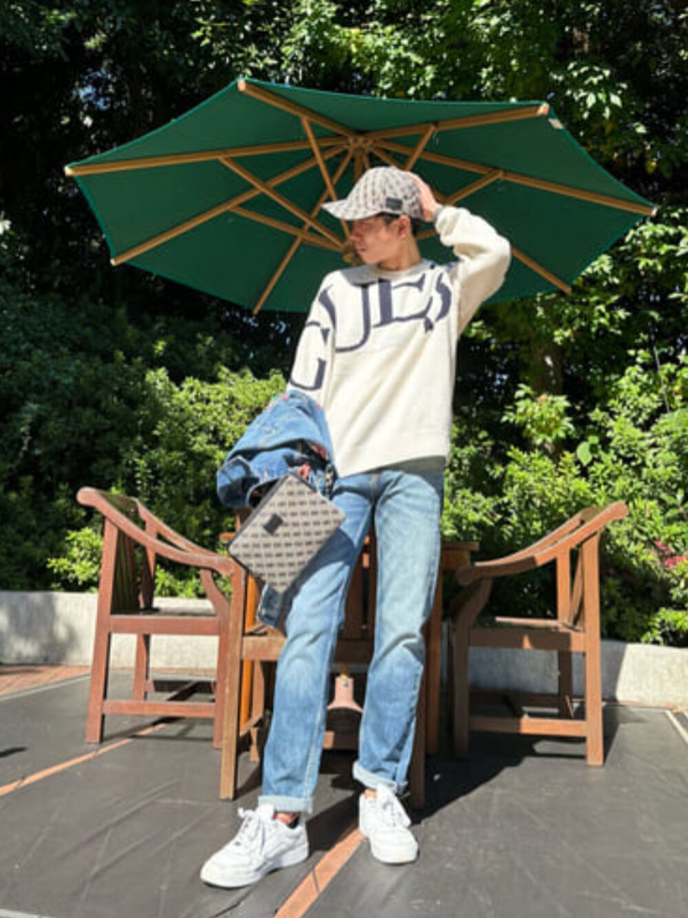 グレー系のショルダーバッグ、ホワイト系のニット/セーター、ブルー系のデニムパンツを着用したメンズの秋コーディネートの1枚目の写真