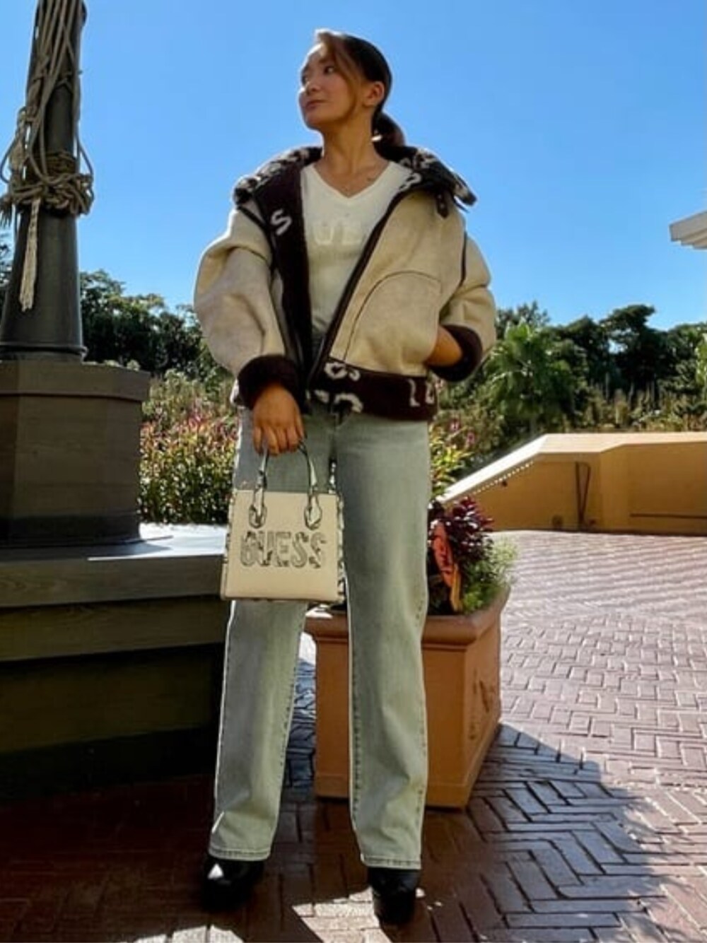 ブルー系のデニムパンツ、ベージュ系のトートバッグ、ブラウン系のブルゾンを着用したレディースの秋コーディネートの1枚目の写真