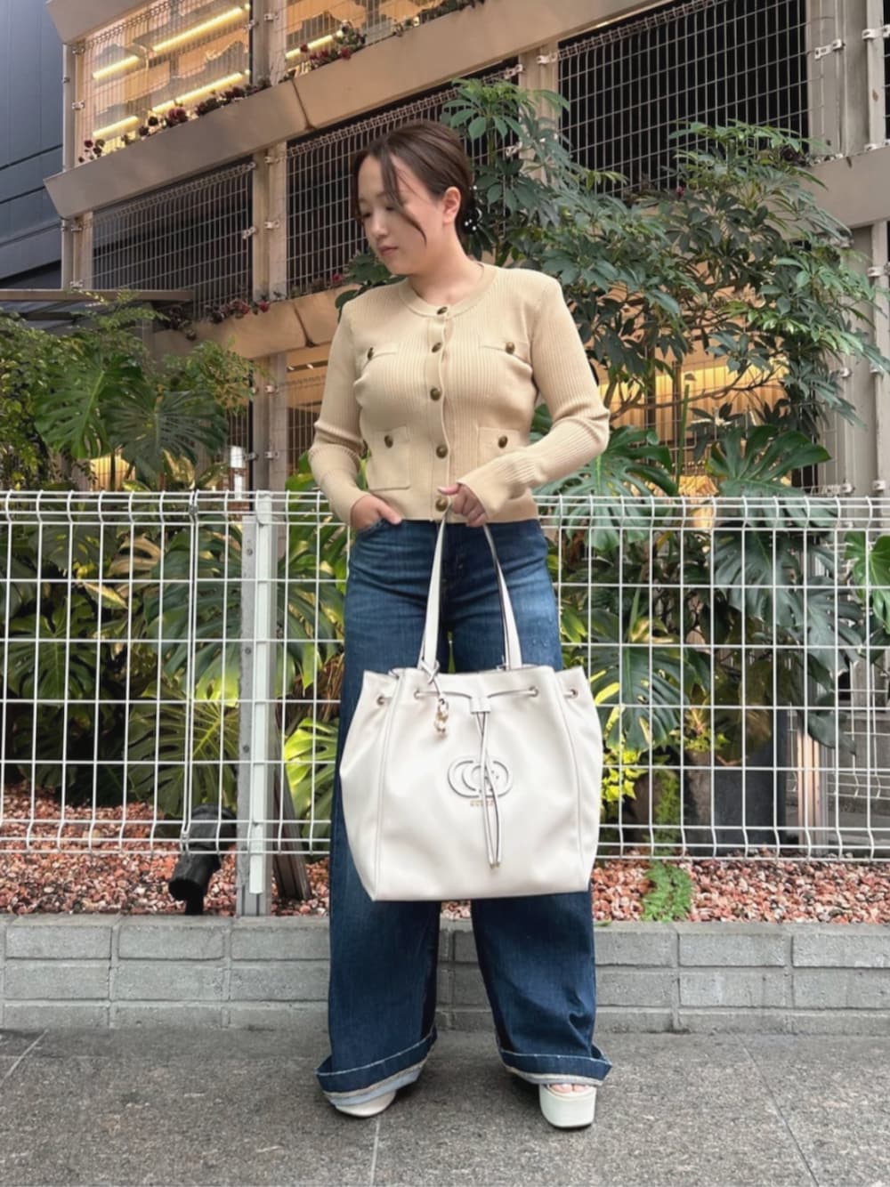 ベージュ系のカーディガン/ボレロ、ブルー系のデニムパンツ、ホワイト系のトートバッグを着用したレディースの秋コーディネートの1枚目の写真