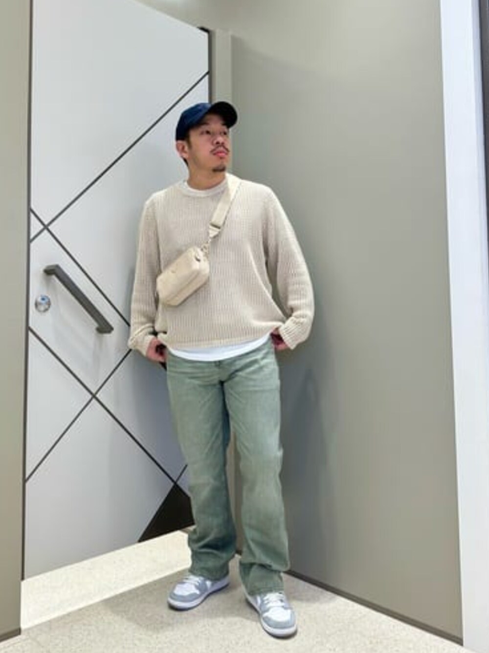 ベージュ系のショルダーバッグ、ホワイト系のTシャツ/カットソー、ベージュ系のニット/セーターを着用したメンズの春コーディネートの1枚目の写真