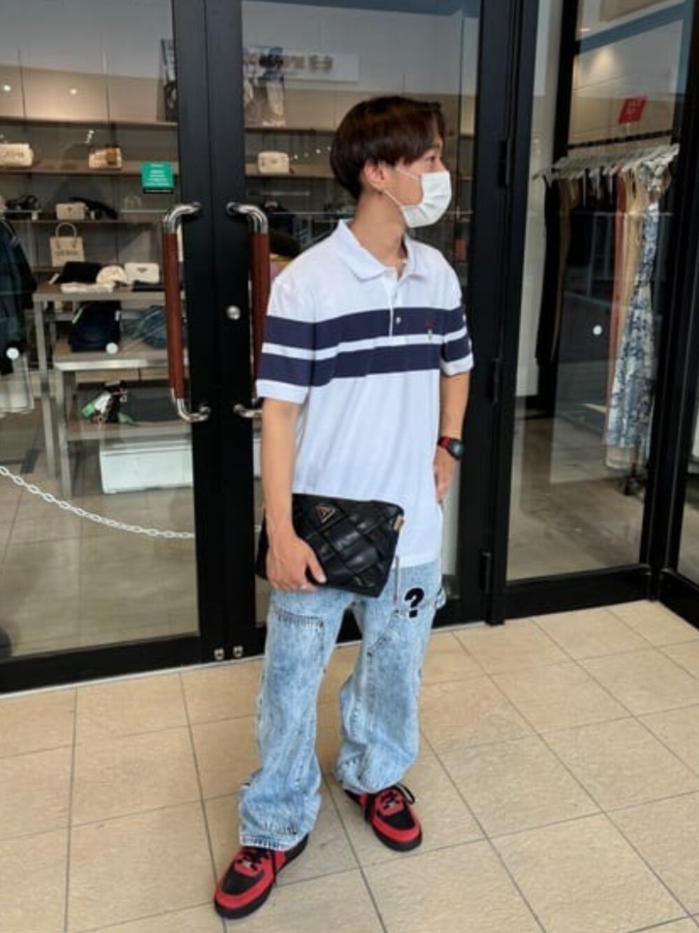 ブラック系のショルダーバッグ、ホワイト系のポロシャツ、ブルー系のデニムパンツを着用したメンズの夏コーディネートの1枚目の写真