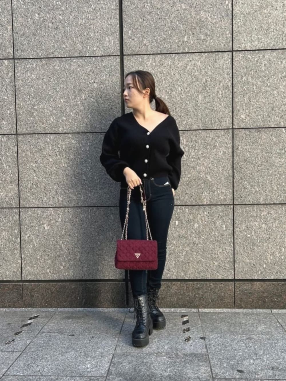 ブルー系のデニムパンツ、ブラック系のカーディガン/ボレロ、レッド系のショルダーバッグを着用したレディースの秋コーディネートの1枚目の写真