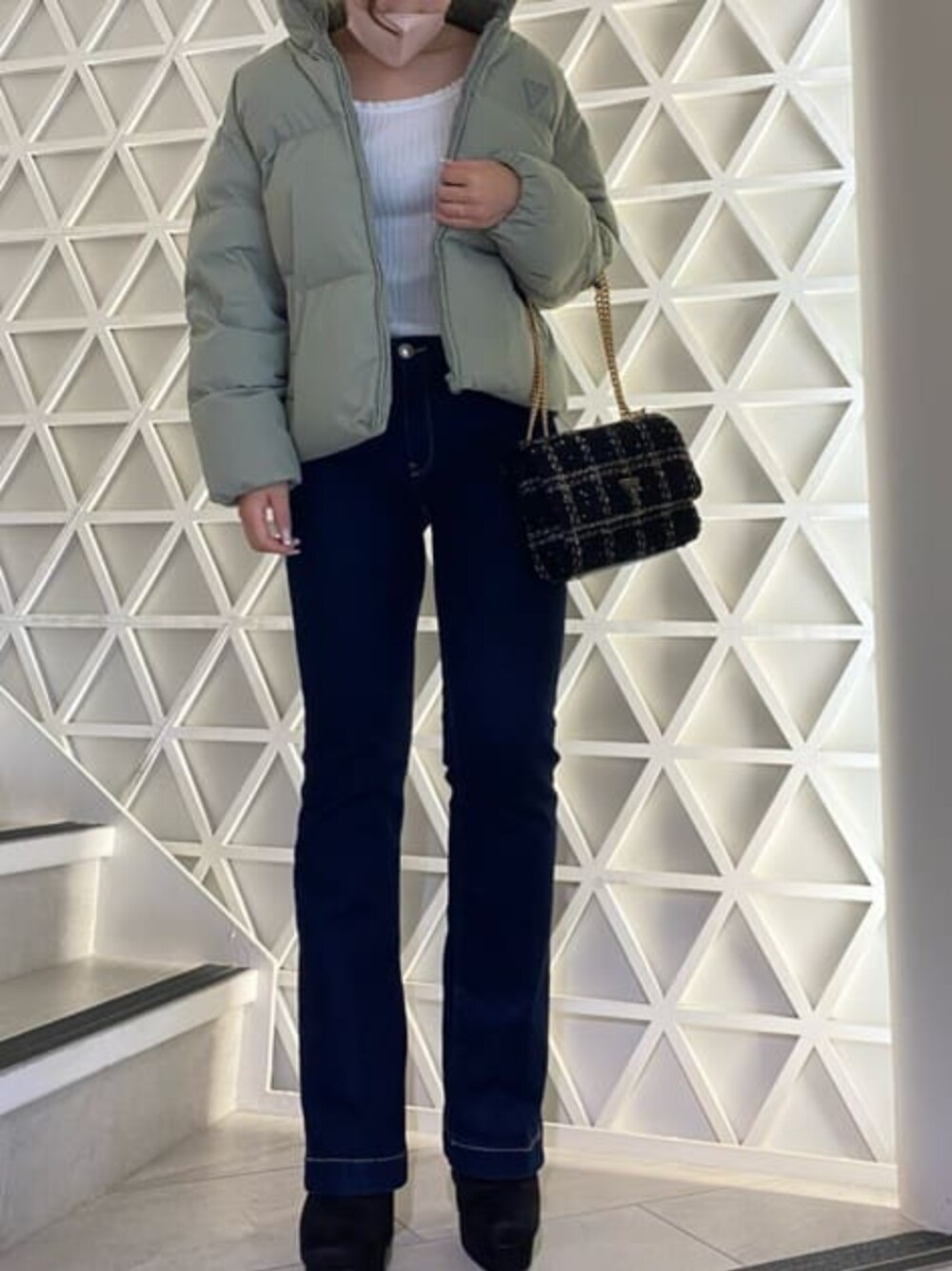 ブルー系のデニムパンツ、グリーン系のダウンジャケット/コート、ホワイト系のニット/セーターを着用したレディースの秋コーディネートの1枚目の写真