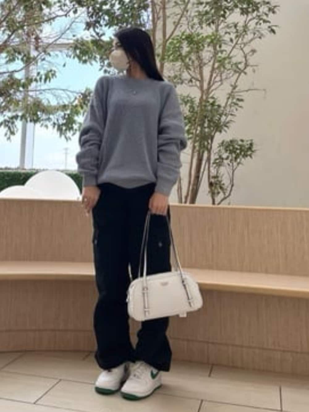 ブラック系のカーゴパンツ、ホワイト系のショルダーバッグ、ブルー系のニット/セーターを着用したレディースの春コーディネートの1枚目の写真