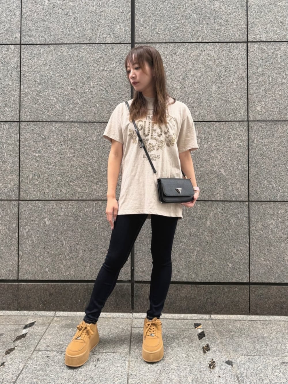 ブラック系のショルダーバッグ、ブルー系のデニムパンツ、ベージュ系のTシャツ/カットソーを着用したレディースの秋コーディネートの1枚目の写真