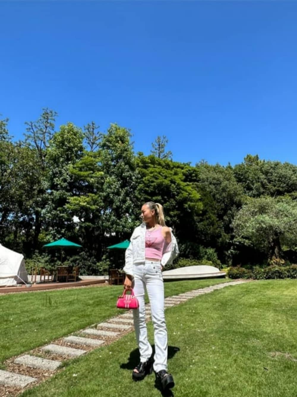 ホワイト系のデニムパンツ、ピンク系のタンクトップ、ホワイト系のブルゾンを着用したレディースの夏コーディネートの1枚目の写真