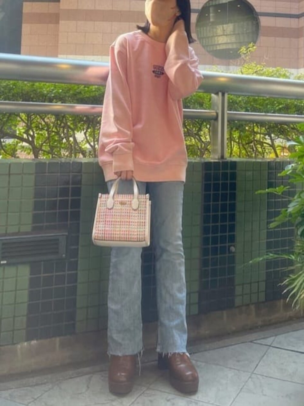 ピンク系のスウェット、ブルー系のデニムパンツ、ホワイト系のトートバッグを着用したレディースの冬コーディネートの1枚目の写真