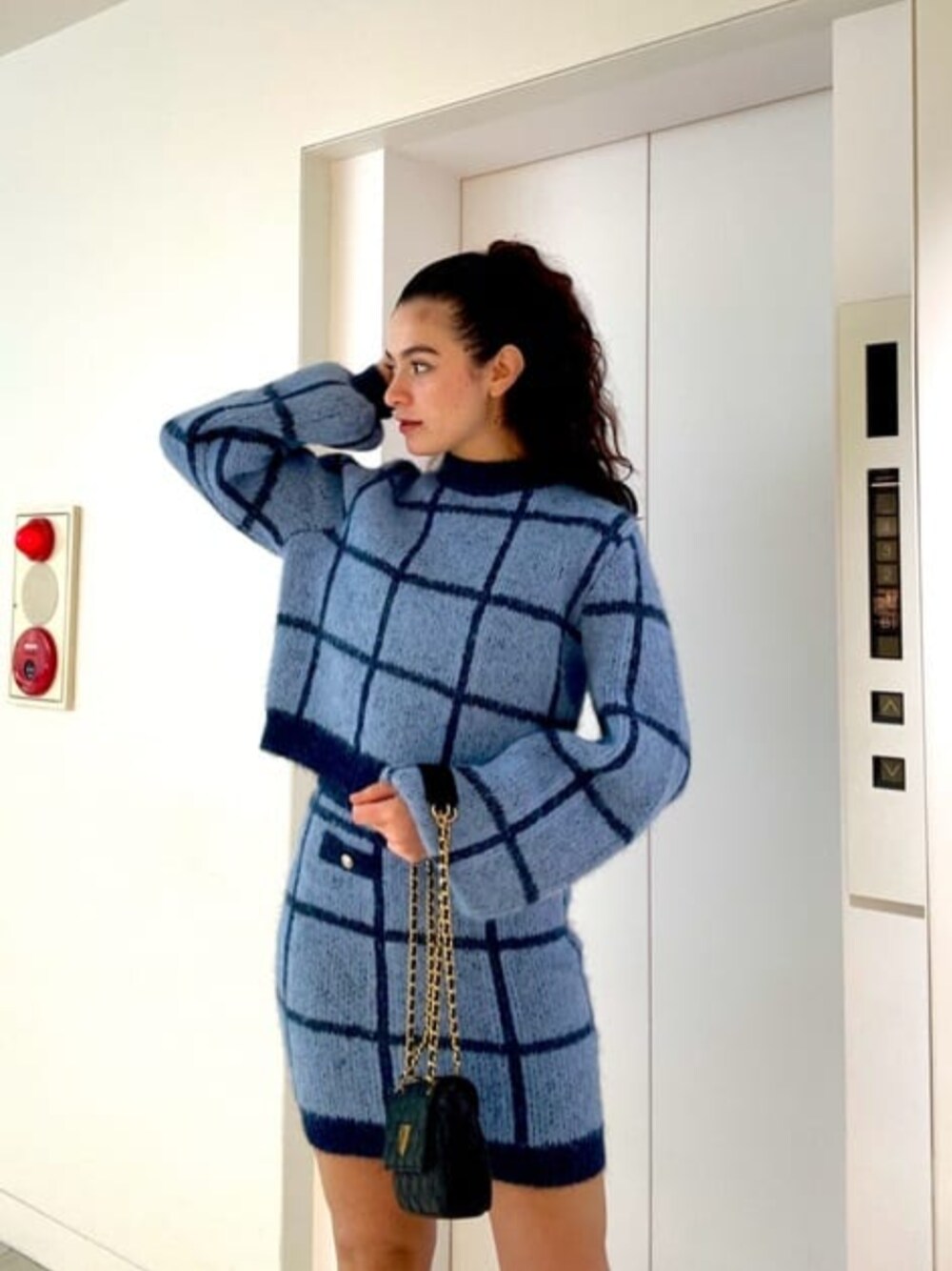 ブルー系のスカート、ブラック系のショルダーバッグ、ブルー系のニット/セーターを着用したレディースの冬コーディネートの1枚目の写真