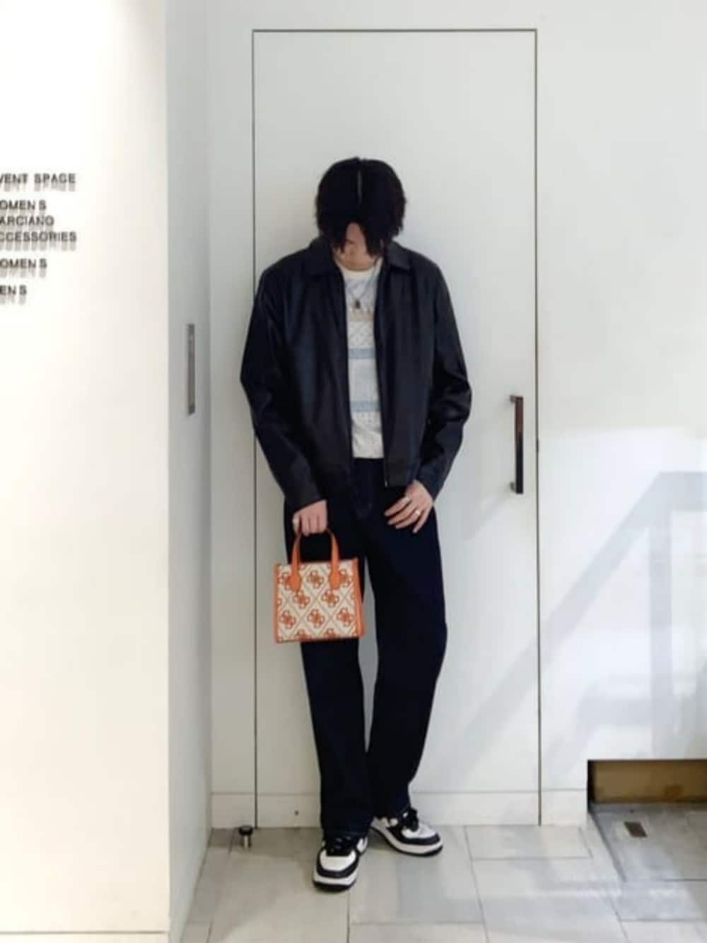 ブルー系のデニムパンツ、オレンジ系のトートバッグ、ブラック系のブルゾンを着用したメンズの秋コーディネートの1枚目の写真