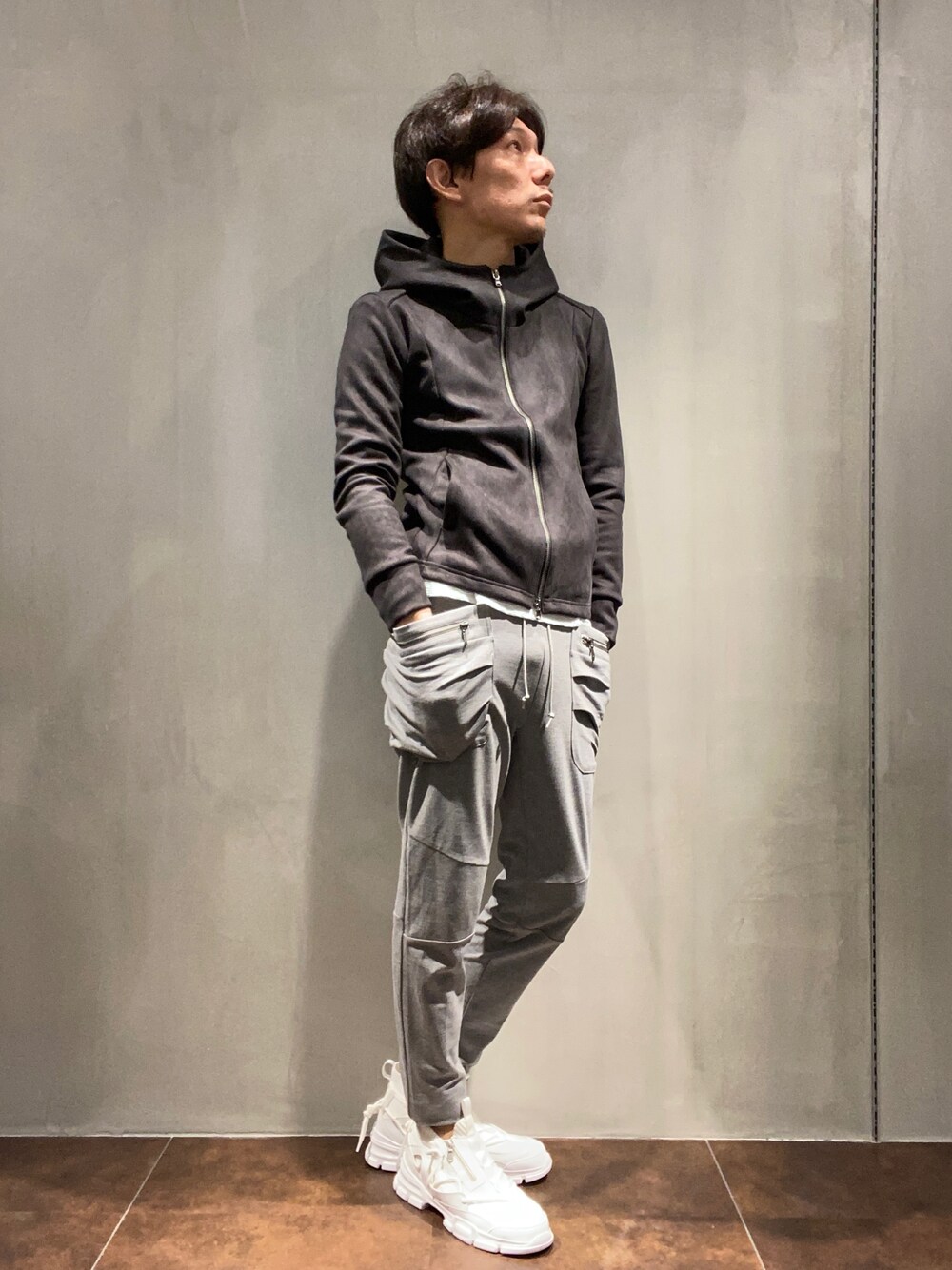 ブラック系のパーカー、グレー系のその他パンツ、ホワイト系のドレスシューズを着用したメンズの秋コーディネートの1枚目の写真