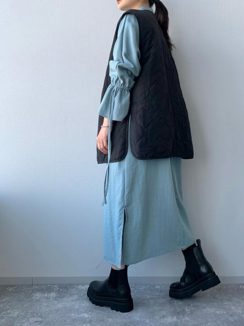 ブラック系のブーツ、ブラック系のその他アウター、ブルー系のワンピースを着用したレディースの冬コーディネートの3枚目の写真