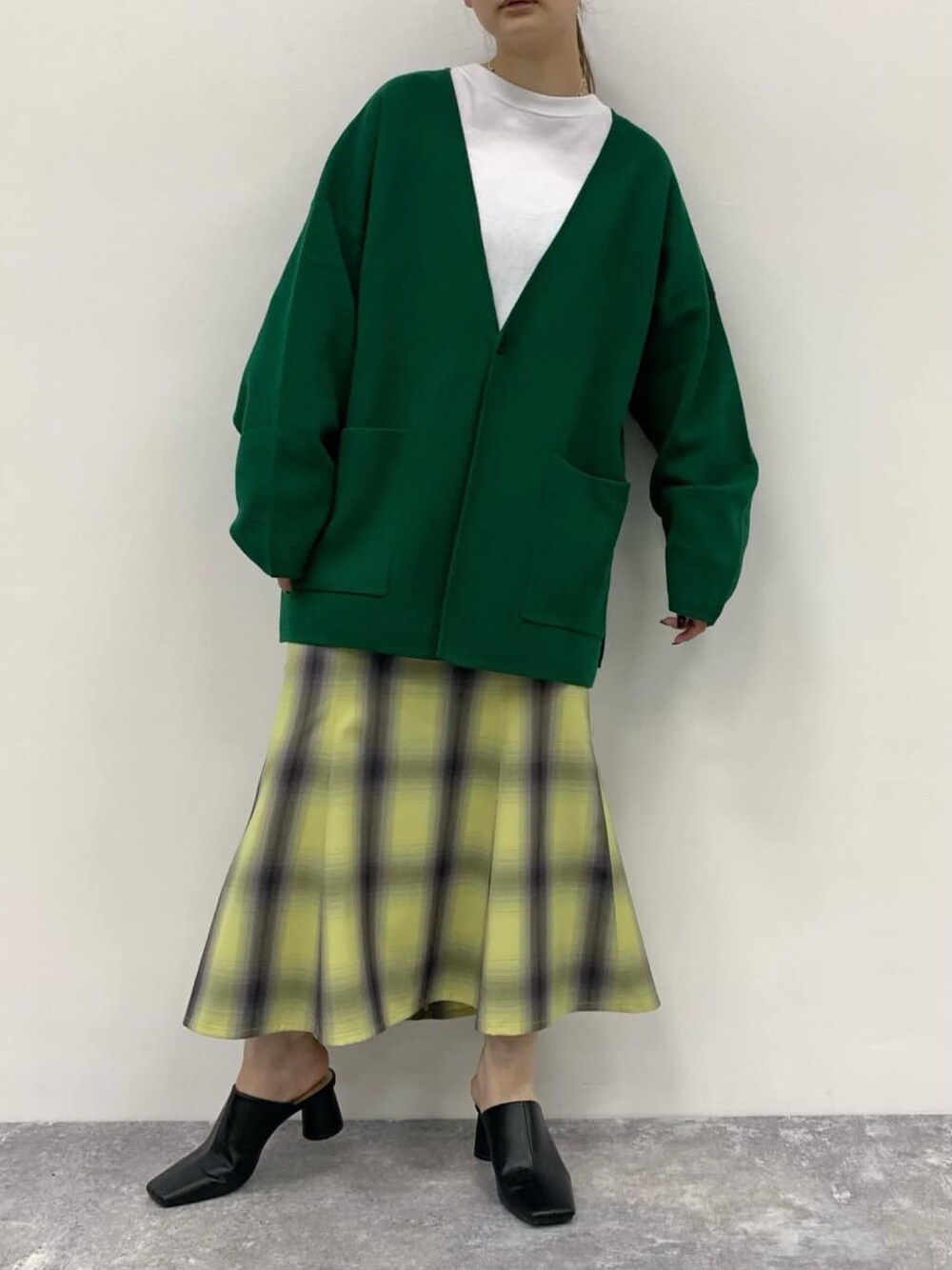 グリーン系のカーディガン/ボレロ、イエロー系のスカートを着用したレディースの冬コーディネートの2枚目の写真
