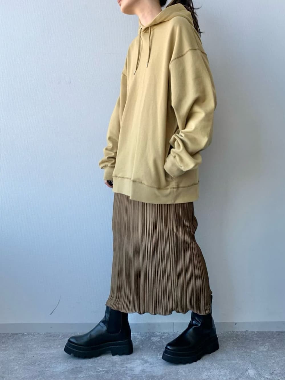 ブラック系のブーツ、ブラウン系のスカート、イエロー系のパーカーを着用したレディースの冬コーディネートの2枚目の写真