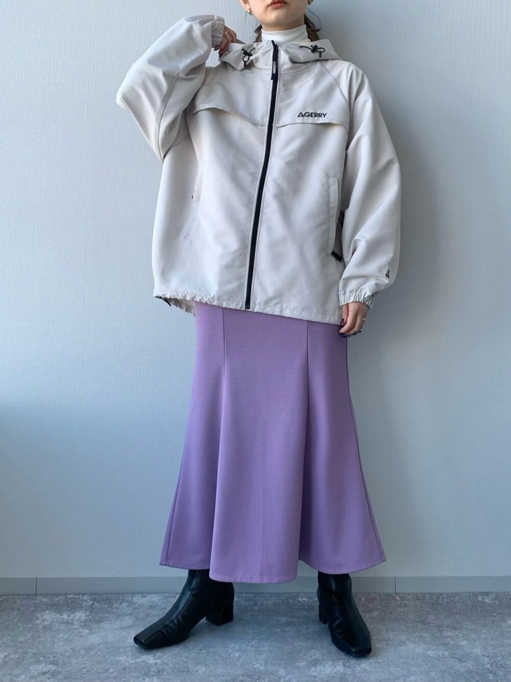 ブラック系のブーツ、パープル系のスカート、ホワイト系のマウンテンパーカーを着用したレディースの冬コーディネートの2枚目の写真