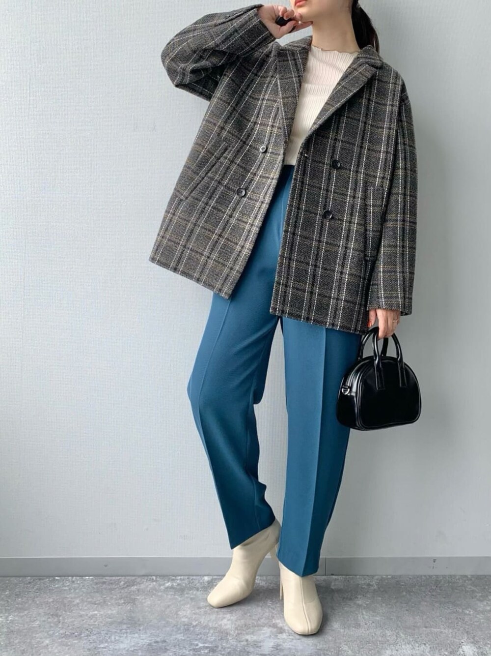 ブルー系のスラックス、ホワイト系のブーツ、ブラック系のボストンバッグを着用したレディースの冬コーディネートの2枚目の写真