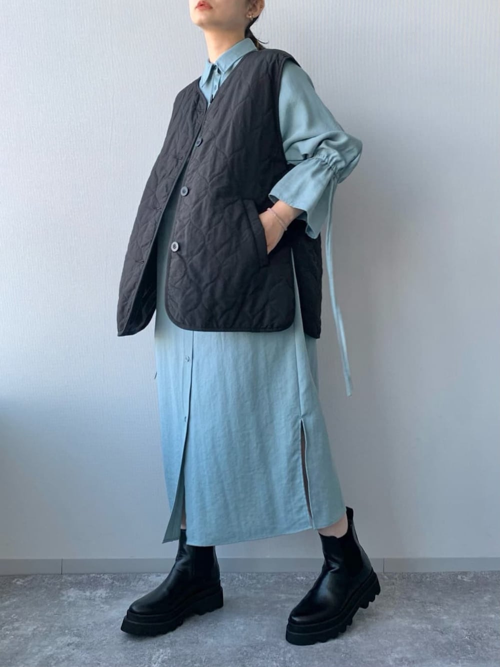 ブラック系のブーツ、ブラック系のその他アウター、ブルー系のワンピースを着用したレディースの冬コーディネートの2枚目の写真