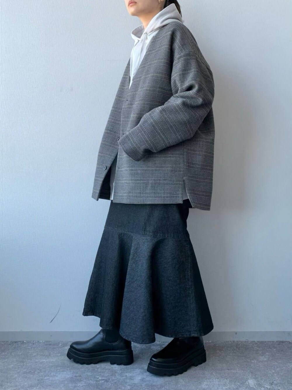 ブラック系のブーツ、ブルー系のスカート、グレー系のノーカラージャケットを着用したレディースの冬コーディネートの2枚目の写真