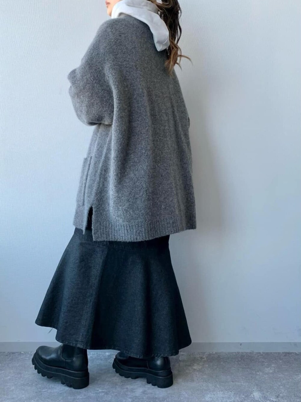 ブルー系のスカート、ブラック系のブーツ、グレー系のカーディガン/ボレロを着用したレディースの冬コーディネートの2枚目の写真