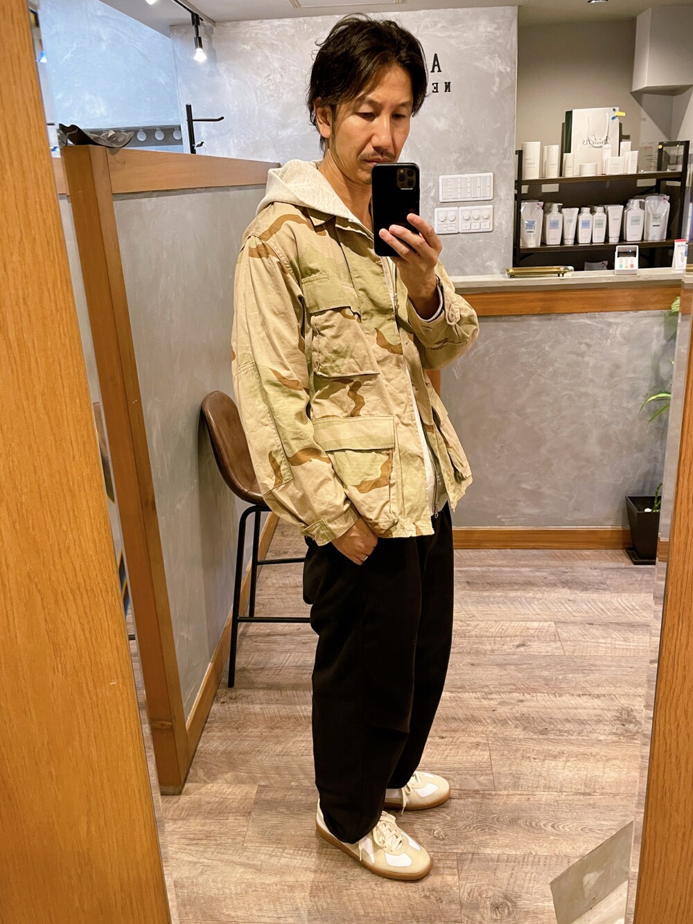 ホワイト系のスニーカー、ブルー系のパンツ、その他のミリタリージャケットを着用したメンズの秋コーディネートの1枚目の写真