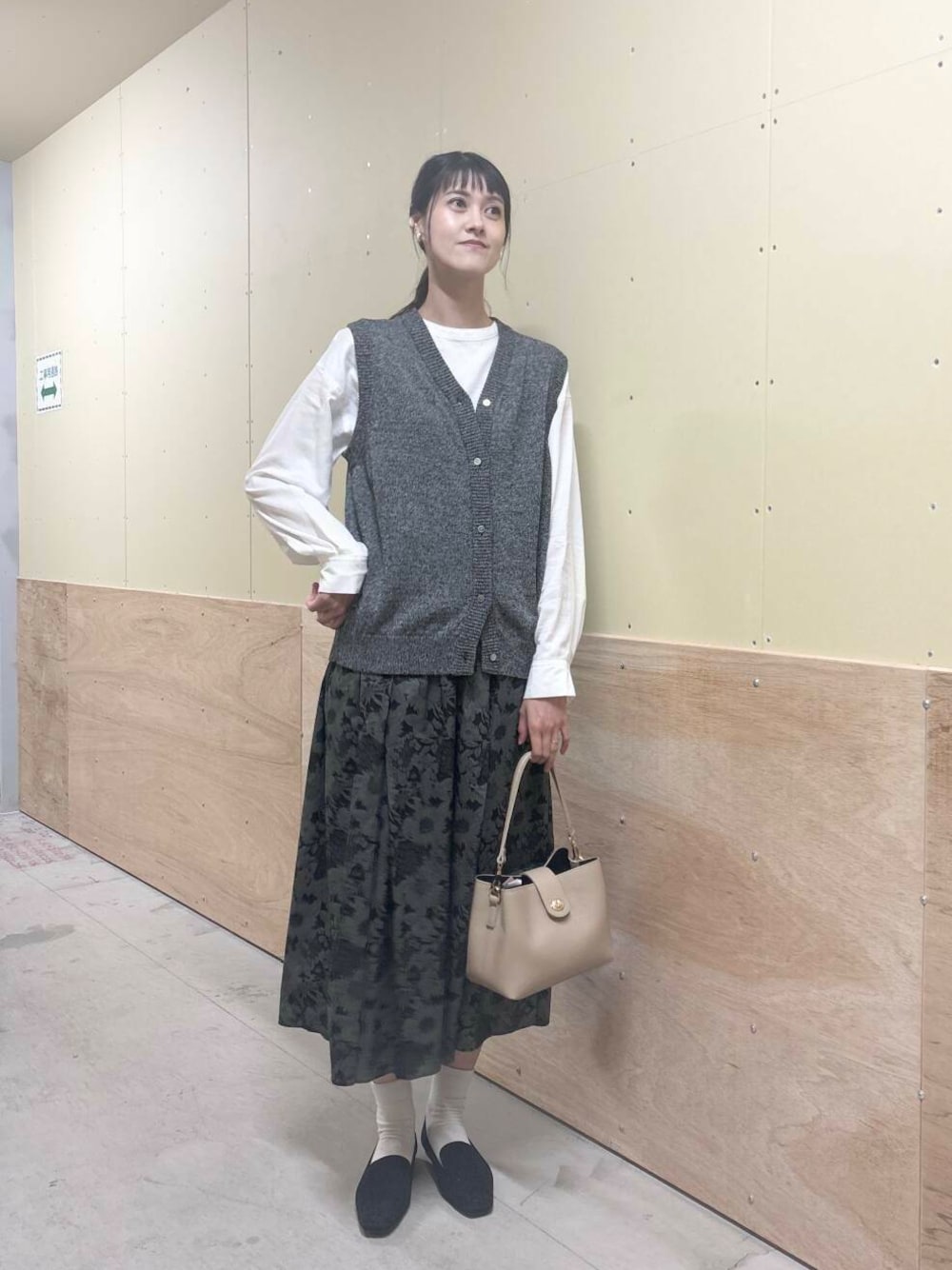 ベージュ系のショルダーバッグ、ブラック系のスカート、ブラック系のローファーを着用したレディースの秋コーディネートの1枚目の写真