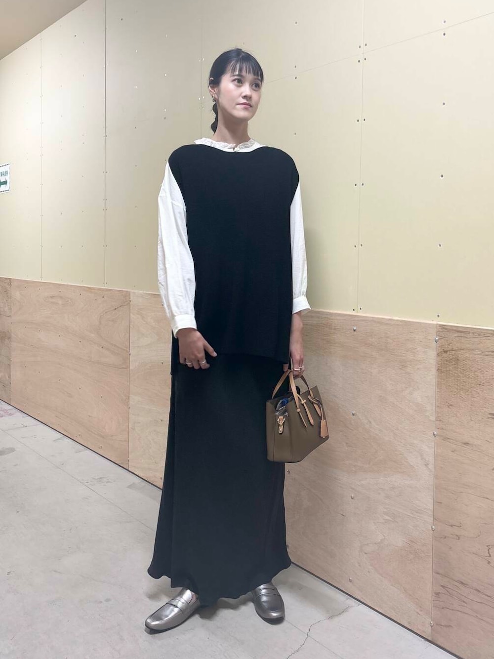 ブラウン系のハンドバッグ、ホワイト系のシャツ/ブラウス、ブラック系のベストを着用したレディースの秋コーディネートの1枚目の写真