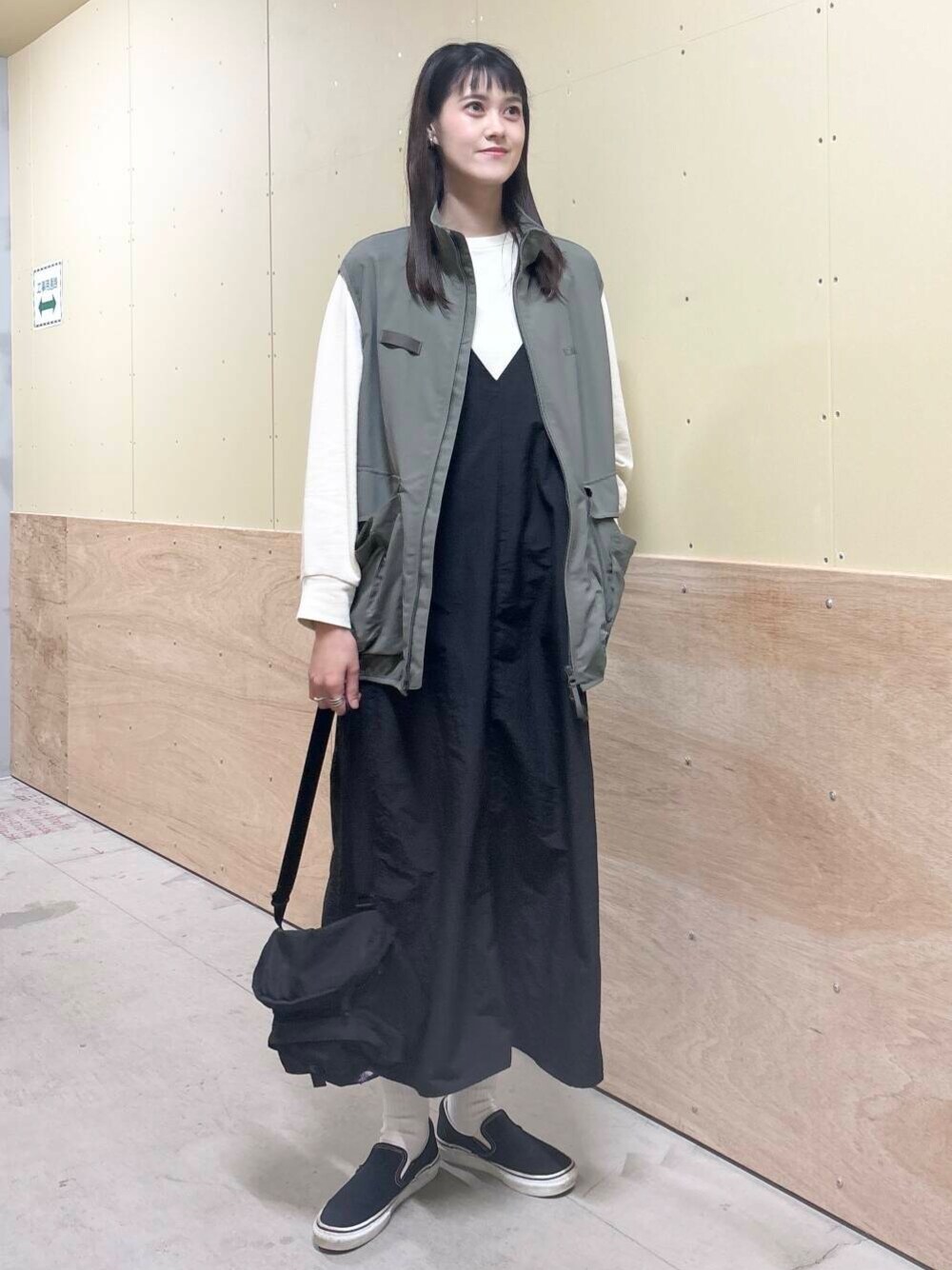 グリーン系のベスト、ブラック系のワンピース、ベージュ系のTシャツ/カットソーを着用したレディースの秋コーディネートの1枚目の写真