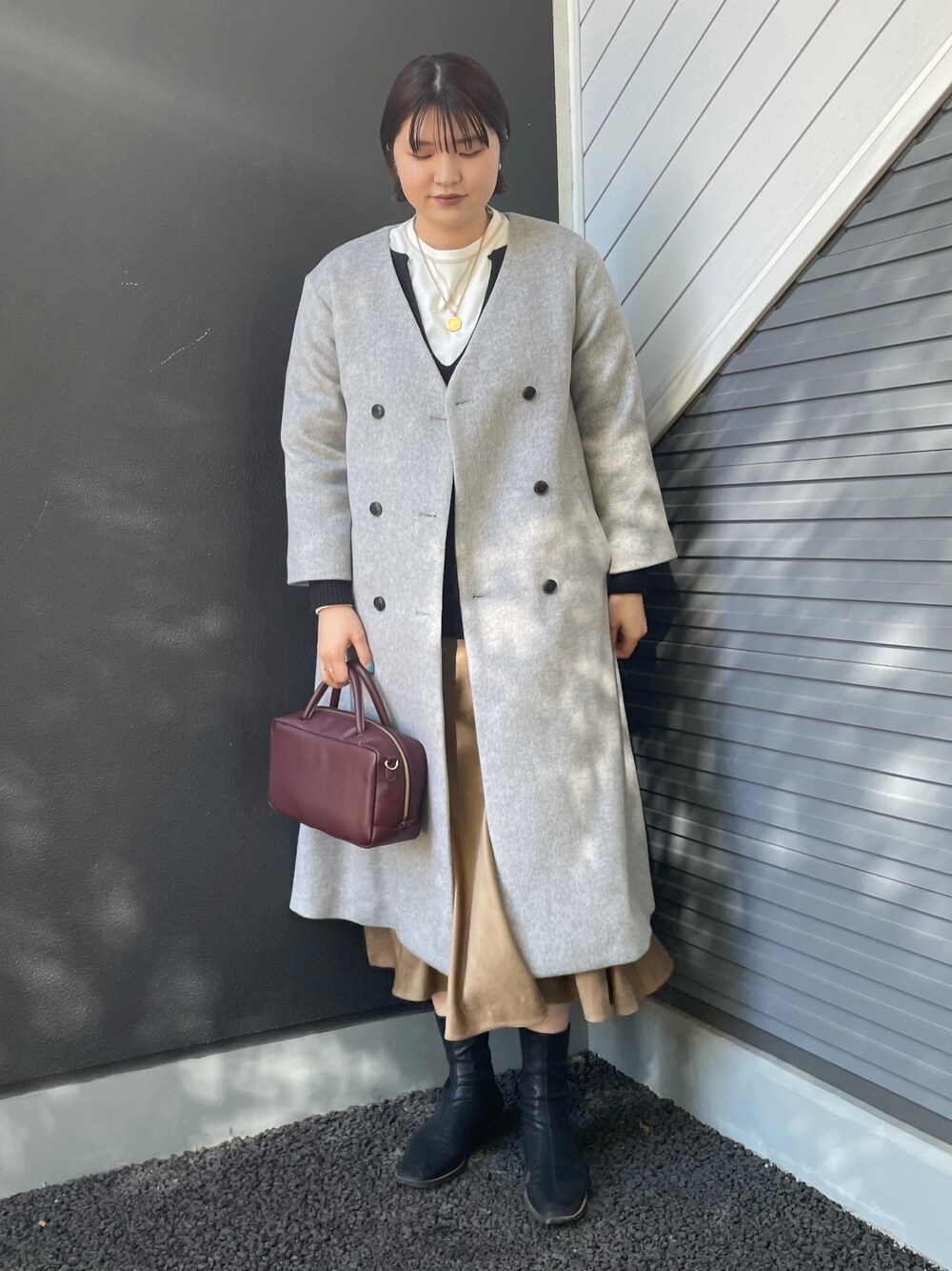 レッド系のボストンバッグ、グレー系のその他アウター、ホワイト系のTシャツ/カットソーを着用したレディースの冬コーディネートの1枚目の写真