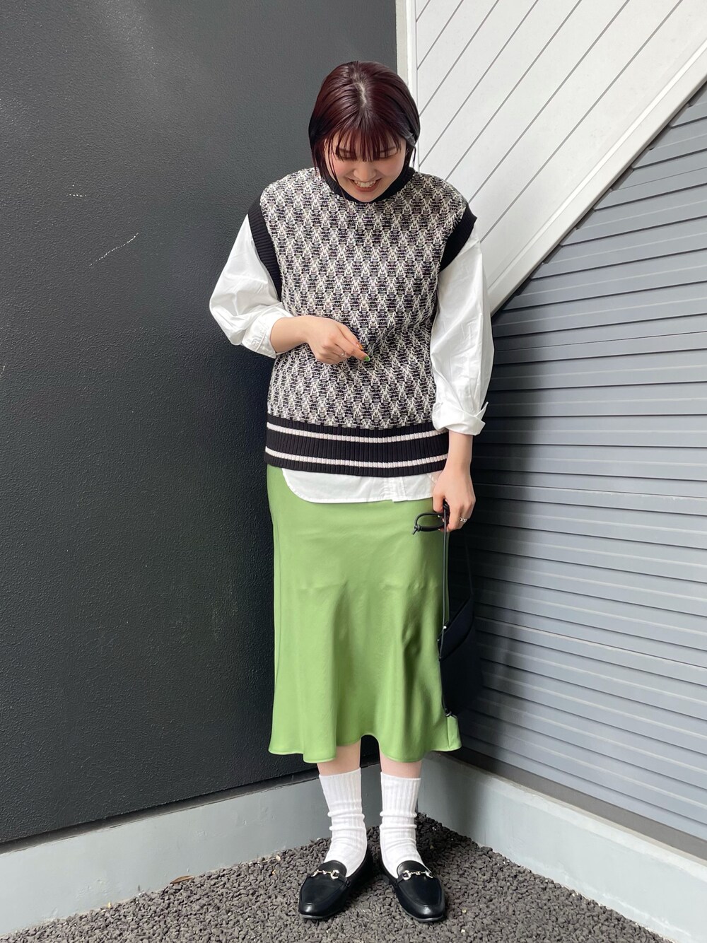 ブラック系のベスト、ホワイト系のシャツ/ブラウス、グリーン系のスカートを着用したレディースの冬コーディネートの1枚目の写真