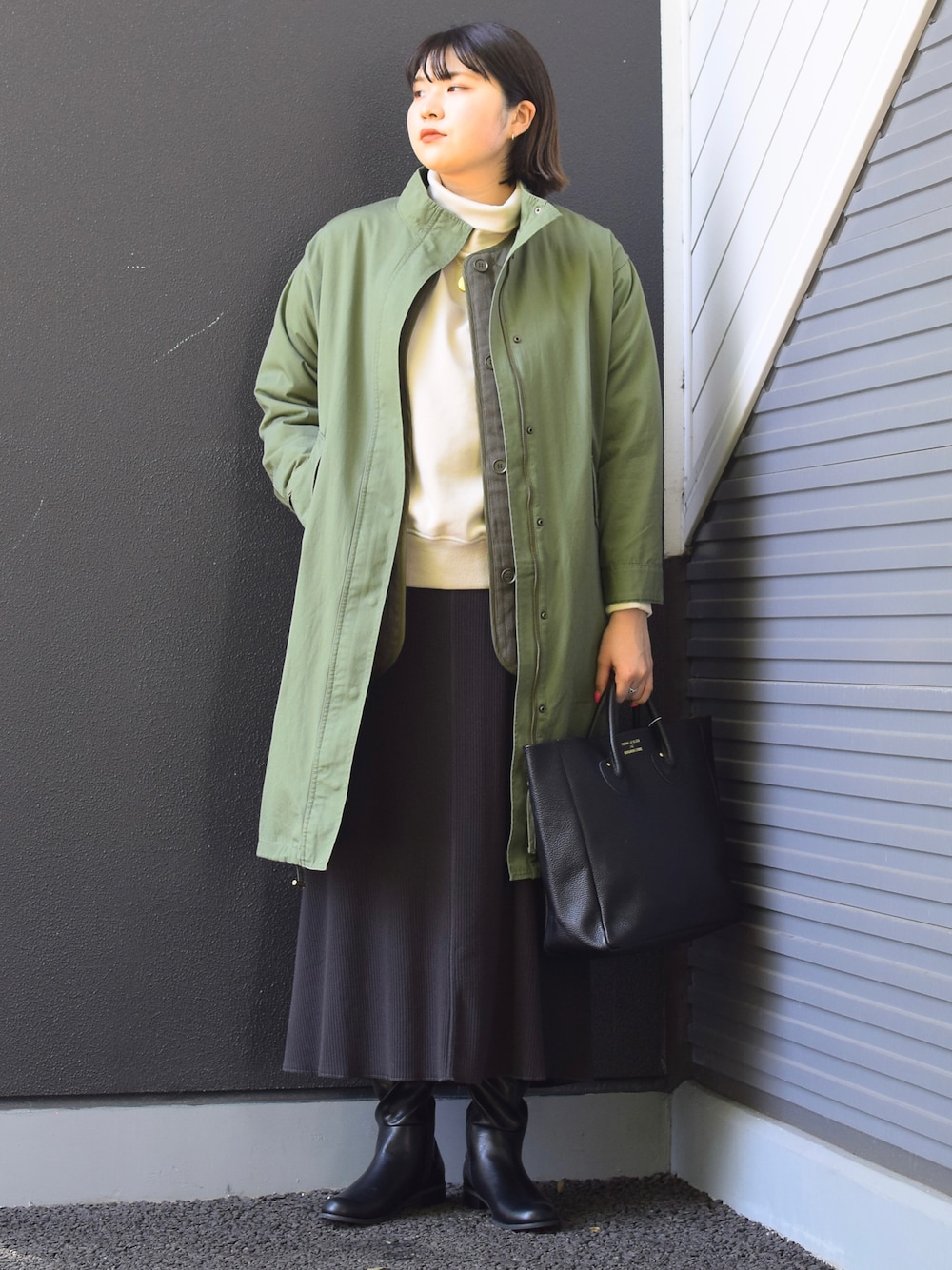 グリーン系のミリタリージャケット、ブラック系のトートバッグ、グレー系のスカートを着用したレディースの冬コーディネートの1枚目の写真