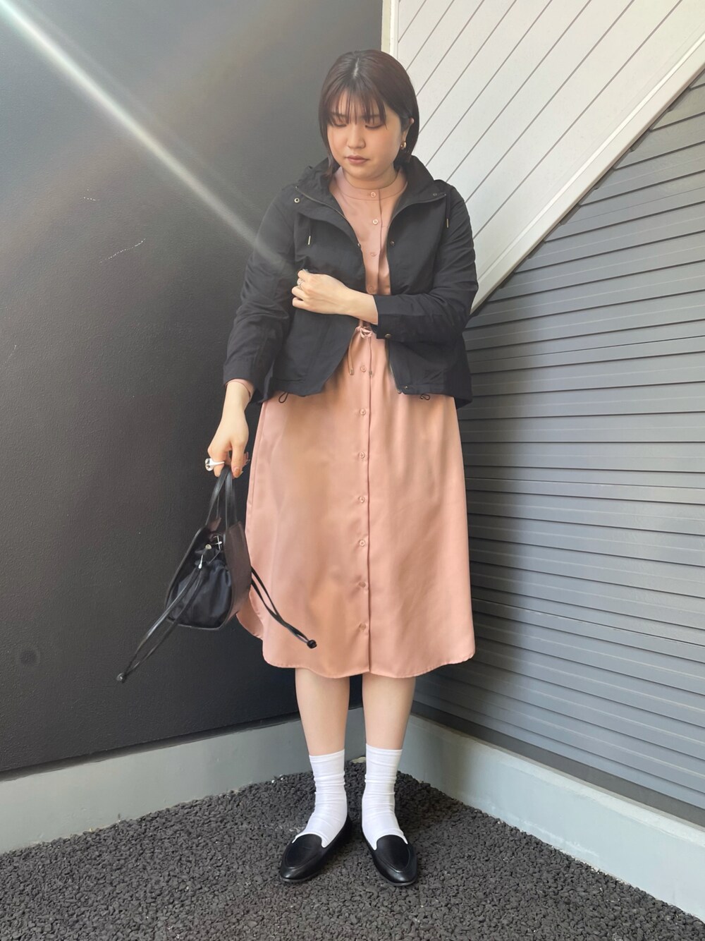 ブラック系のマウンテンパーカー、ピンク系のワンピース、ブラック系のスリッポンを着用したレディースの春コーディネートの1枚目の写真