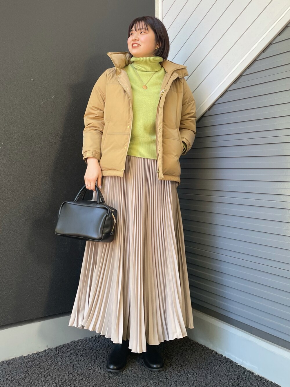 グリーン系のニット/セーター、ベージュ系のダウンジャケット/コート、ブラック系のボストンバッグを着用したレディースの冬コーディネートの1枚目の写真
