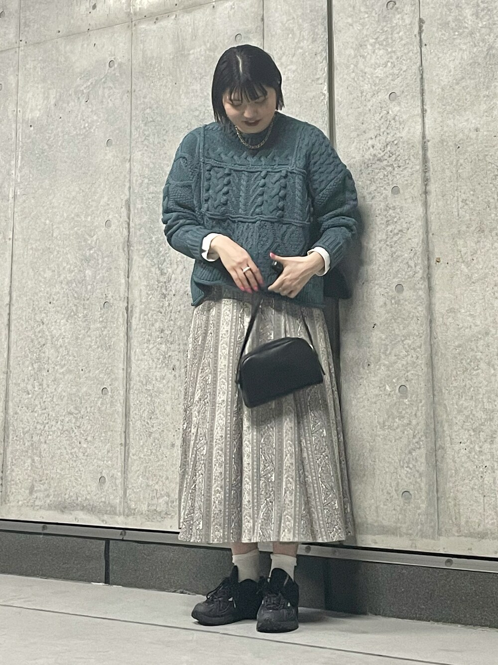 ブルー系のニット/セーター、ホワイト系のシャツ/ブラウス、ベージュ系のスカートを着用したレディースの秋コーディネートの1枚目の写真