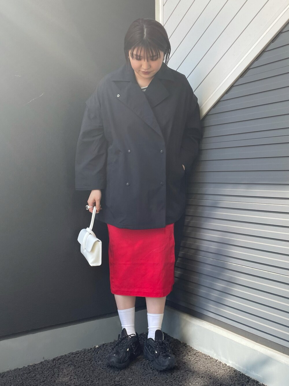 ブルー系のポンチョ、ホワイト系のショルダーバッグ、レッド系のスカートを着用したレディースの冬コーディネートの1枚目の写真